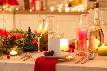 Festive table setting with Christmas decorations and glowing lights in kitchen at evening, closeup