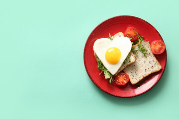 Plate with tasty fried egg, toasts, tomatoes and arugula on turquoise background