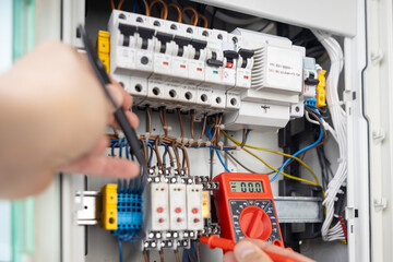 Hands Using Multimeter for Electrical Testing in Panel