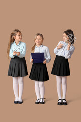 Cute girls in school uniform with clipboard and molecular models on beige background