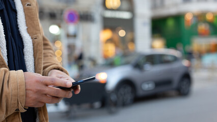 Customer using smartphone app for electric car rental service in city street