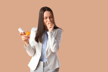 Young woman with pills for sore throat on brown background