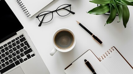 Flat lay of eyeglasses, coffee cup, pen, and laptop on a white desk. Work and productivity concept