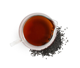 Glass jug of oil with sesame seeds on white background