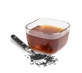 Glass bowl of oil with spoon and sesame seeds on white background