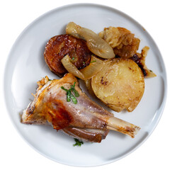 Juicy baked lamb chops accompanied by roasted potatoes and onion slices, topped with fresh herbs and served with side of red sauce for dipping. Isolated over white background.