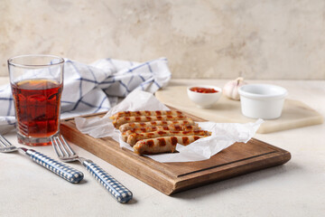 Wooden board with tasty grilled sausages and glass of beer on white background