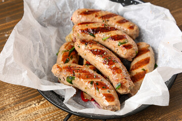 Frying pan with tasty grilled sausages on wooden background