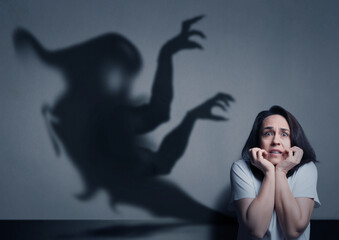 Woman scared by monster. Scary shadow in room