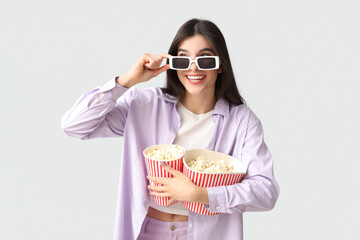 Young pretty woman in 3D cinema eyeglasses with popcorn buckets on white background