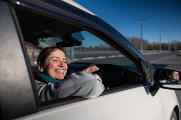 Happy Caucasian woman sitting behind the wheel looking out the window and smiling. 