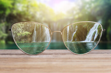 Glasses against beautiful landscape. View through lenses more clear. Vision correction
