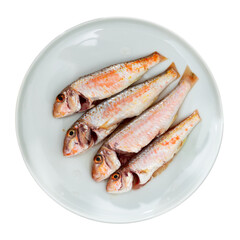 Against background of wooden table there is plate with raw Atlantic fish, prepared for cooking and processing. Raw uncooked Atlantic mullus barbatus carcasses, garlic, lemon, decanter with olive oil