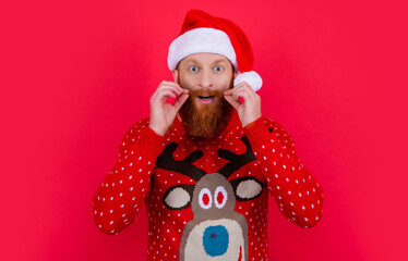 surprised xmas man in santa claus red hat. xmas holiday. bearded santa man at xmas isolated on red