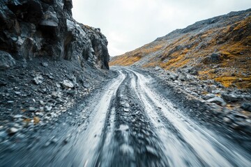A winding dirt road passes through rugged terrain of rocky mountains, ideal for off-road adventures or scenic views