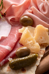 Tagliere con prosciutto crudo, prosciutto cotto, mortadella e parmigiano, antipasti italiani, cibo europeo 