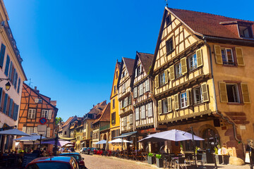 View of historic center of French city of Colmar with paved streets and picturesque half-timbered houses painted in traditional Alsatian colors in summer