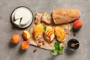 Baking paper of peach bruschetta with ricotta, basil, almond nuts and bowl of honey on grey...