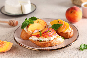 Plate of peach bruschetta with ricotta and mint on white background