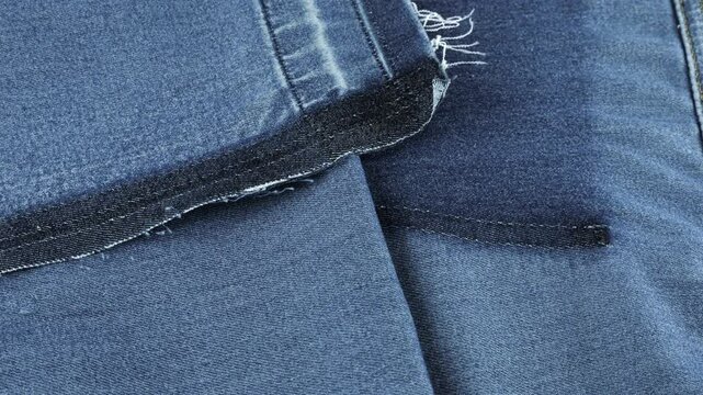 Soft folds of blue denim of a muted shade fabric rotate on the showcase. Textile background on the theme of reuse, recycling clothing and textile for the purpose of preserving the environment. 