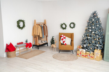 Naklejka premium Interior of hallway with Christmas tree, coat rack and armchair