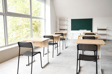 Interior of empty classroom with blackboard and desks