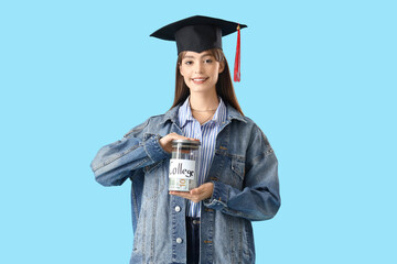 Female student in graduation hat with jar of money for college on blue background. Education...