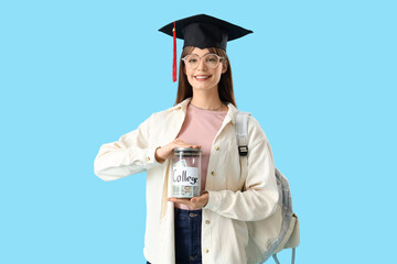 Female student in graduation hat with jar of money for college on blue background. Education...