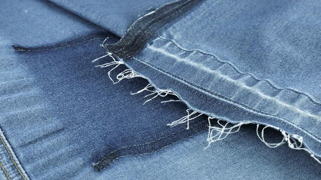 Soft folds of blue denim of a muted shade fabric rotate on the showcase. Textile background on the theme of reuse, recycling clothing and textile for the purpose of preserving the environment.