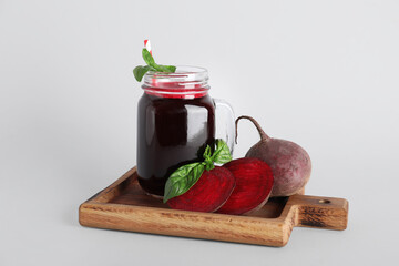 Mason jar of fresh beet juice with basil on grey background