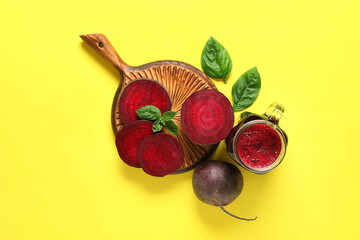 Glass of fresh beet juice with basil and vegetables on yellow background