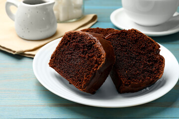 Slices of tasty chocolate sponge cake on light blue wooden table, closeup