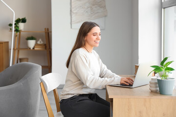 Female programmer working with laptop at desk in room
