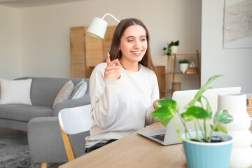 Female programmer with laptop video chatting at desk in room