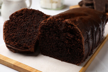 Delicious chocolate sponge cake on white tiled table, closeup