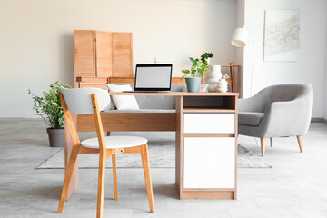 Blank laptop with plant and books on programmer's desk in living room
