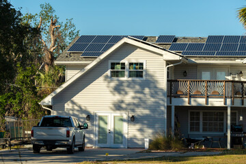 Obraz premium Aerial view of typical american building roof with blue solar photovoltaic panels for producing clean ecological electric energy. Investing in renewable electricity for retirement income concept
