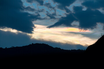 Silhouette of mountains with multi-color lenticular clouds in rural area of Guatemala, city of Latin America, sunset landscape.