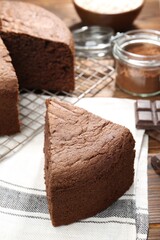 Piece of tasty chocolate sponge cake on wooden table, closeup