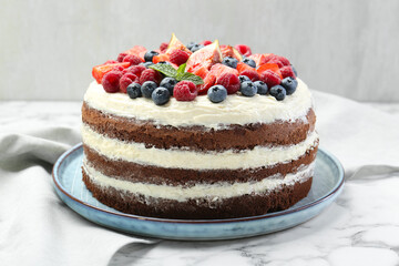 Delicious chocolate sponge cake with berries on white table, closeup