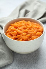 Tasty mashed sweet potato in bowl on gray table, closeup