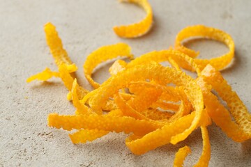 Pile of fresh orange zest on light textured table, closeup