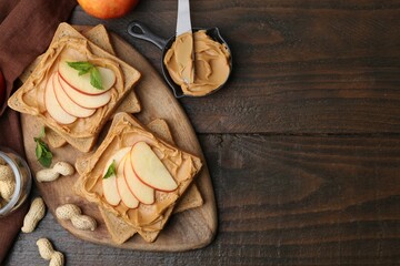 Fototapeta premium Tasty sandwiches with peanut butter, apple, nuts and mint on wooden table, flat lay. Space for text