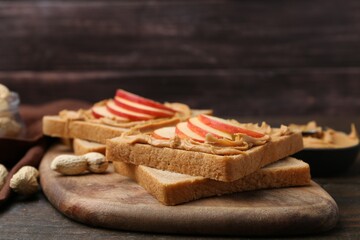 Tasty sandwiches with peanut butter and apple on wooden table, closeup