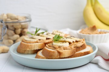 Tasty sandwiches with peanut butter, banana, chia seeds and mint on white table, closeup