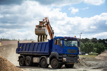Road works. The excavator is loading aggregate onto the dump truck.