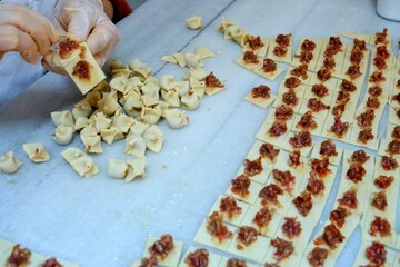 In a manti shop, women are making meat manti, a traditional Turkish culinary delicacy. Close-up of meat being placed into manti. Turkish home cooking. Pastries. Healthy eating.