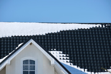 Closeup of house roof top covered with snow in cold winter. Tiled covering of building in...