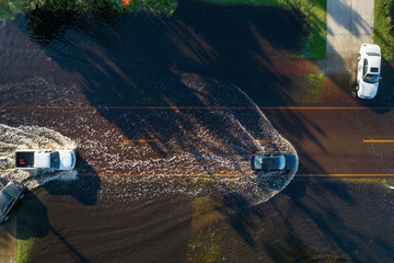 Flooded american street with moving vehicles and surrounded with water houses in Florida...
