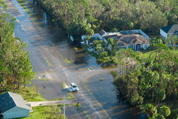 Flooded american street with moving vehicles and surrounded with water houses in Florida...